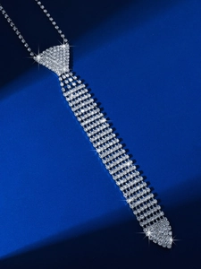 Detailed close-up of a silver rhinestone tie necklace on a dark blue surface