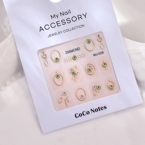 Detail of green and white rhinestone nail art stickers with gold metal frames on pink backing
