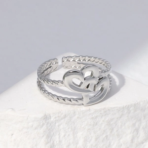 Adjustable silver crossover heart ring with twisted rope band on white stone