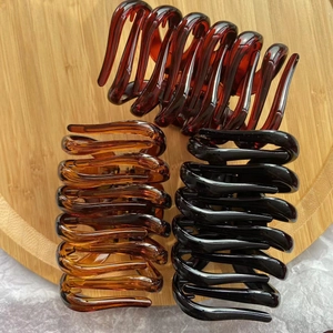 Three large spiral claw clips in amber and black colors on a bamboo tray detail