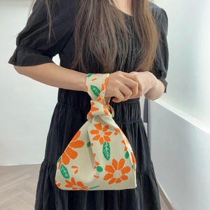 Detail of knitted tote bag with orange floral patterns and single handle design