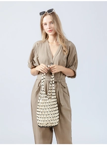 Detailed view of model holding a stylish handmade woven wooden bead bucket bag