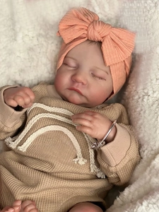 Detail of reborn doll wearing a bow headband and waffle knit top on soft white fleece