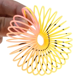 Close-up of flexible orange and yellow gradient plastic spring toy with black spots