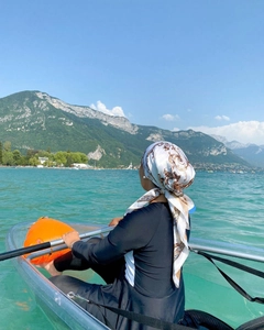 Muslim modest swimwear with baroque print headscarf worn by a woman on a clear boat