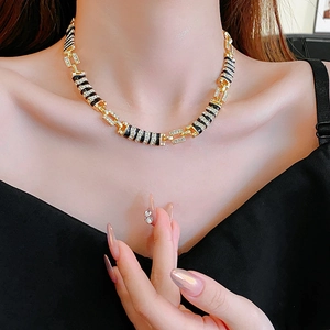 Close-up of golden link necklace with black enamel stripes and sparkling rhinestones