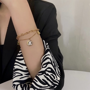 Double-layered golden bear bracelet with white shell pendant worn on a female wrist