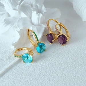 Macro detail of 925 silver hoop earrings with blue and purple sparkling crystals
