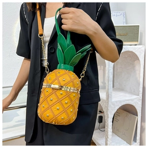 Detail view of stylish pineapple crossbody bag with gold studs and green leaf top