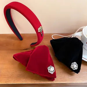Serre-tête et pinces en velours avec camélias et perles sur un bureau en bois