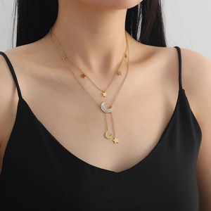 Détail d'un collier multicouche doré avec pendentifs étoile et lune sur modèle