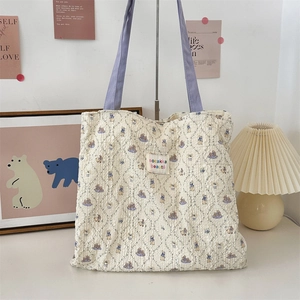 Close-up of quilted cream tote bag featuring vintage rabbit print and purple handle