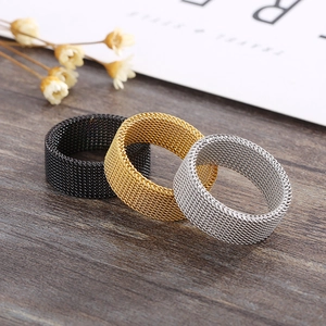 Mesh woven stainless steel rings in black, gold, and silver finishes on a wood background