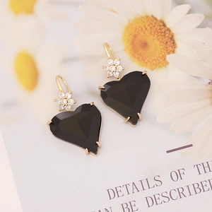 Close-up of black asymmetric heart earrings with gold flower zircon inlay and hooks