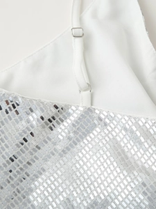Dettaglio delle paillettes argentate e del tessuto bianco dell'abito da festa