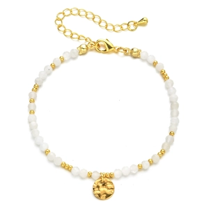 Macro detail of faceted white crystal beads and gold hammered round charm bracelet