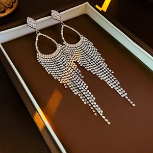 Macro detail of luxury silver tassel earrings with sparkling rhinestones in a gift box