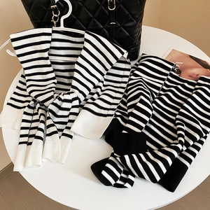 Flat lay of striped knit shawl and top with a Vogue magazine on a white table