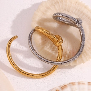 Detailed close-up of gold and silver twisted knot open bangles with water droplets