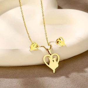 Detailed view of gold heart necklace and cat stud earrings set on a white tray