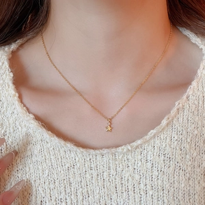 Primo piano di una collana con ciondolo a stella d'oro e zircone su una modella in maglia