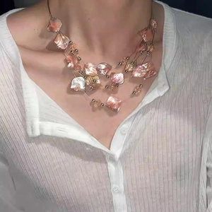 Collier bohème multicouche avec perles en coquillage rose et accents dorés sur un mannequin