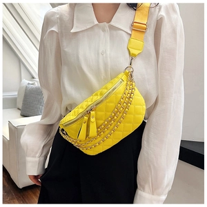 Close-up of bright yellow quilted chest bag with golden chains and adjustable strap