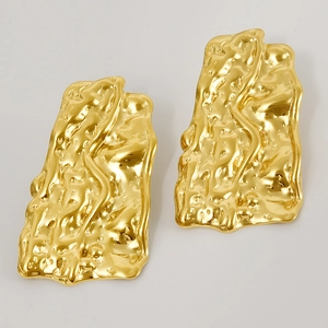 Close-up of golden irregular textured earrings with unique pleated surface design