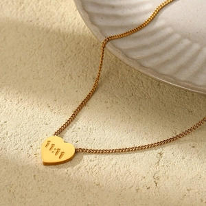 Collier doré avec pendentif cœur gravé 11:11 et zircon sur fond texturé de couleur beige