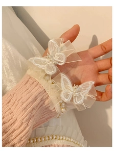 Close-up of white lace butterfly hair clips with pearls on a pink knit sweater