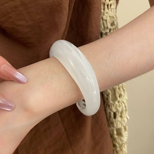 Detailaufnahme eines breiten, weiß-transparenten Acryl-Armreifs mit Marmortextur