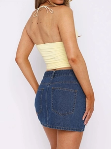 Vista trasera de top halter amarillo con encaje y minifalda vaquera azul