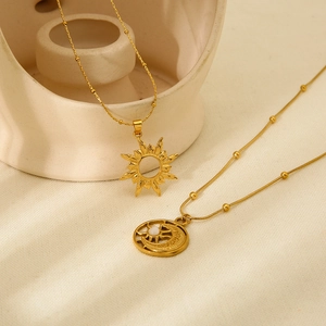 18k gold plated stainless steel necklaces with sun and moon pendants on beige fabric
