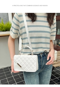 Close-up of white quilted handbag featuring a stylish fabric shoulder strap on a model