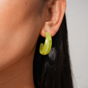 Close-up of a model wearing the bright yellow-green C-shaped resin earring with marble texture