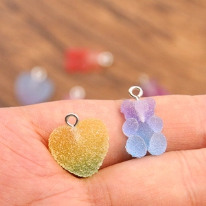 Pendentifs ours et cœur en résine dégradée faits à la main tenus sur le bout des doigts