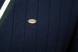 Dettaglio ravvicinato del cardigan blu scuro con trama a coste verticali e logo in metallo