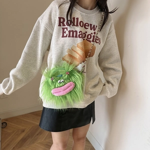 Girl wearing a fuzzy green monster plush crossbody bag with colorful braided straps