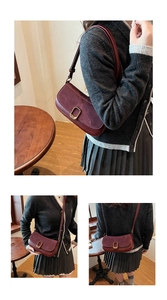 Detail view of burgundy frosted suede shoulder bag featuring a gold rectangular metal buckle