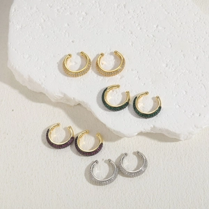 Luxurious C-shaped zircon ear cuffs in gold and silver plating on stone background