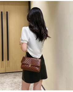 Brown quilted chain bag with V-pattern and golden lock worn by a model in detail