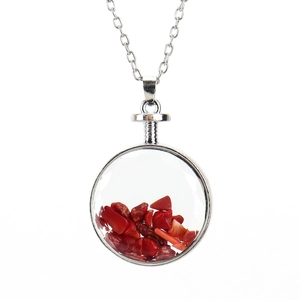 Macro shot of circular glass pendant necklace with red natural stone filling