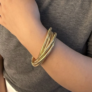 Close-up of layered golden coil bracelet showing detailed metallic spring texture on wrist