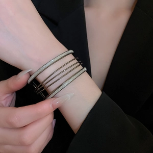 Detail of six-piece stacked gunmetal bracelets set with frosted glitter and smooth textures