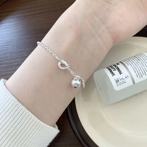 Macro detail of a S925 sterling silver beaded bracelet with knot and heart charm on a desk