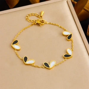 Bracelet chaîne dorée avec breloques cœurs noirs et blancs sur coussin doré