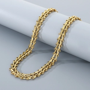 Detail view of a gold V-shaped geometric chain wrapped around a gray cylinder