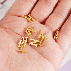 Polished gold initial letter pendants displayed on palm for DIY jewelry making