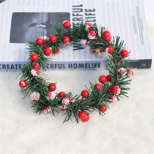 Detail view of a Christmas candle ring featuring red snowy berries and green pine needles