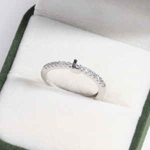 Macro shot of silver letter L ring with pavé diamonds in a dark green velvet box